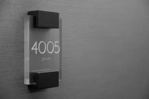 Close-up of a room number sign with raised numerals and Grade 2 Braille dots, an example of ADA-compliant tactile signage